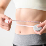 Woman measuring her waist using a tape measure